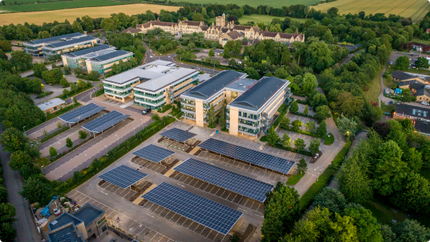 Aerial view of solar carports providing renewable energy and shade in a green landscape near commercial buildings.