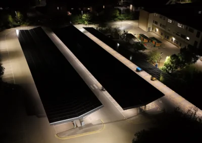 Night aerial of Wharfedale Hospital car park illuminated beneath Bluetop Solar OPTI solar canopies generating clean energy